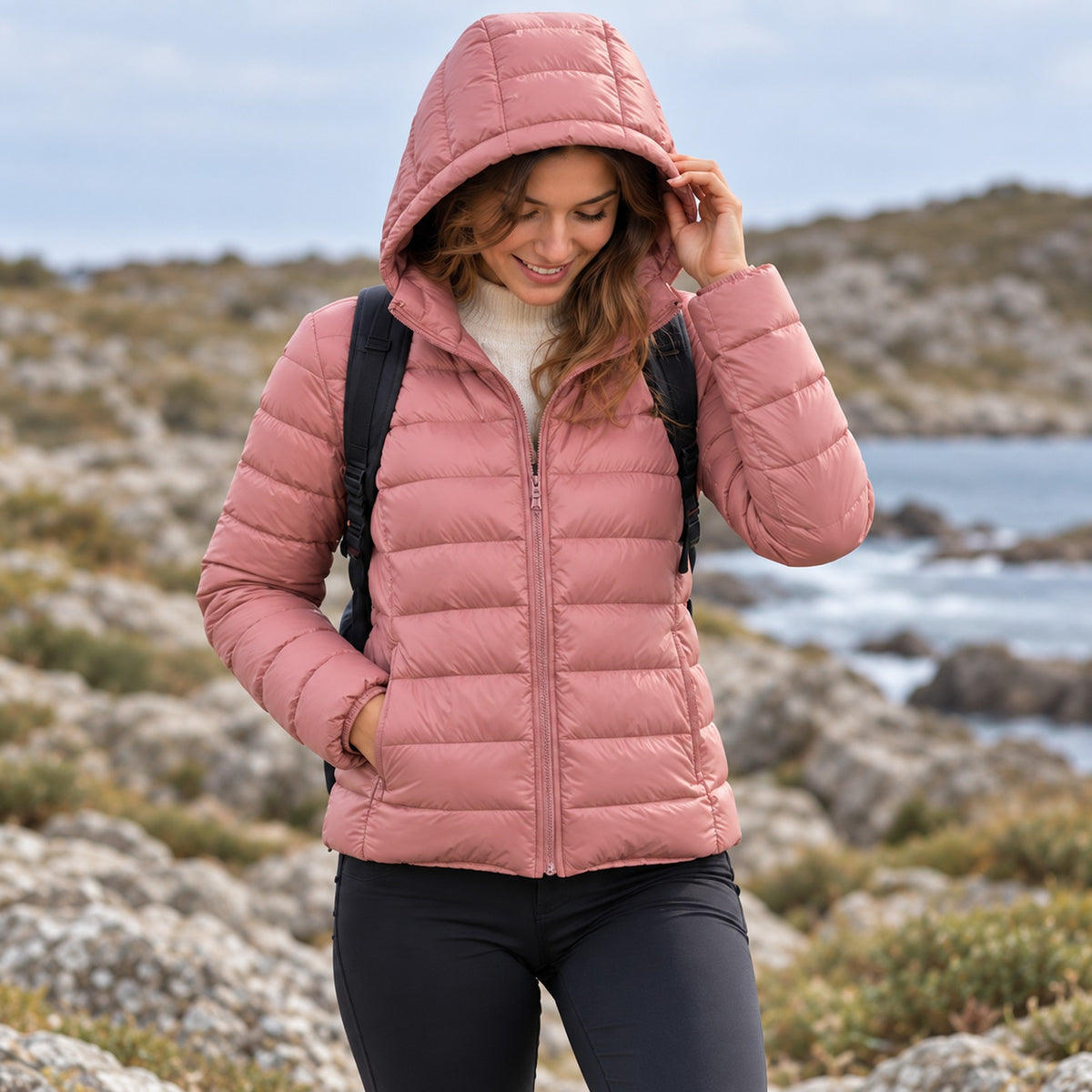 Women's compressible hiking down jacket pink hood up in the mountains